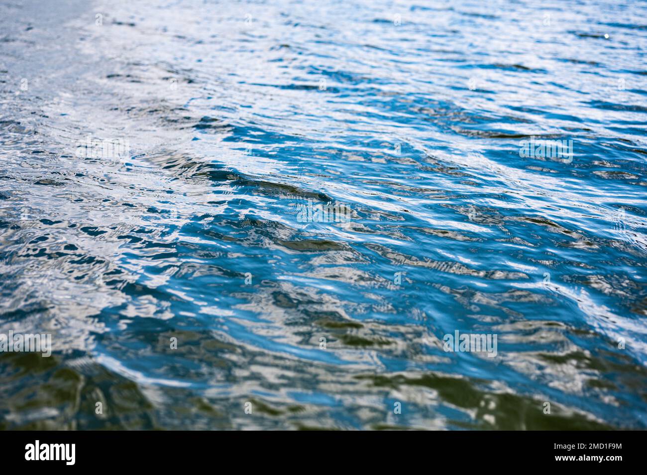 Scatto di primo piano ad alta velocità di un flusso d'acqua ondulato del lago. Blu scuro colori neri della superficie dell'acqua. Foto Stock