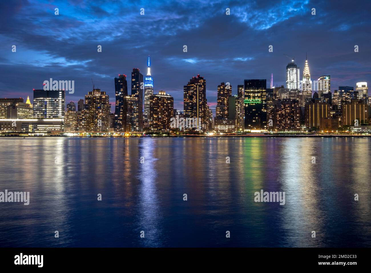 Skyline di Manhattan di notte con l'Empire State Building di fronte all'East River, New York, USA Foto Stock