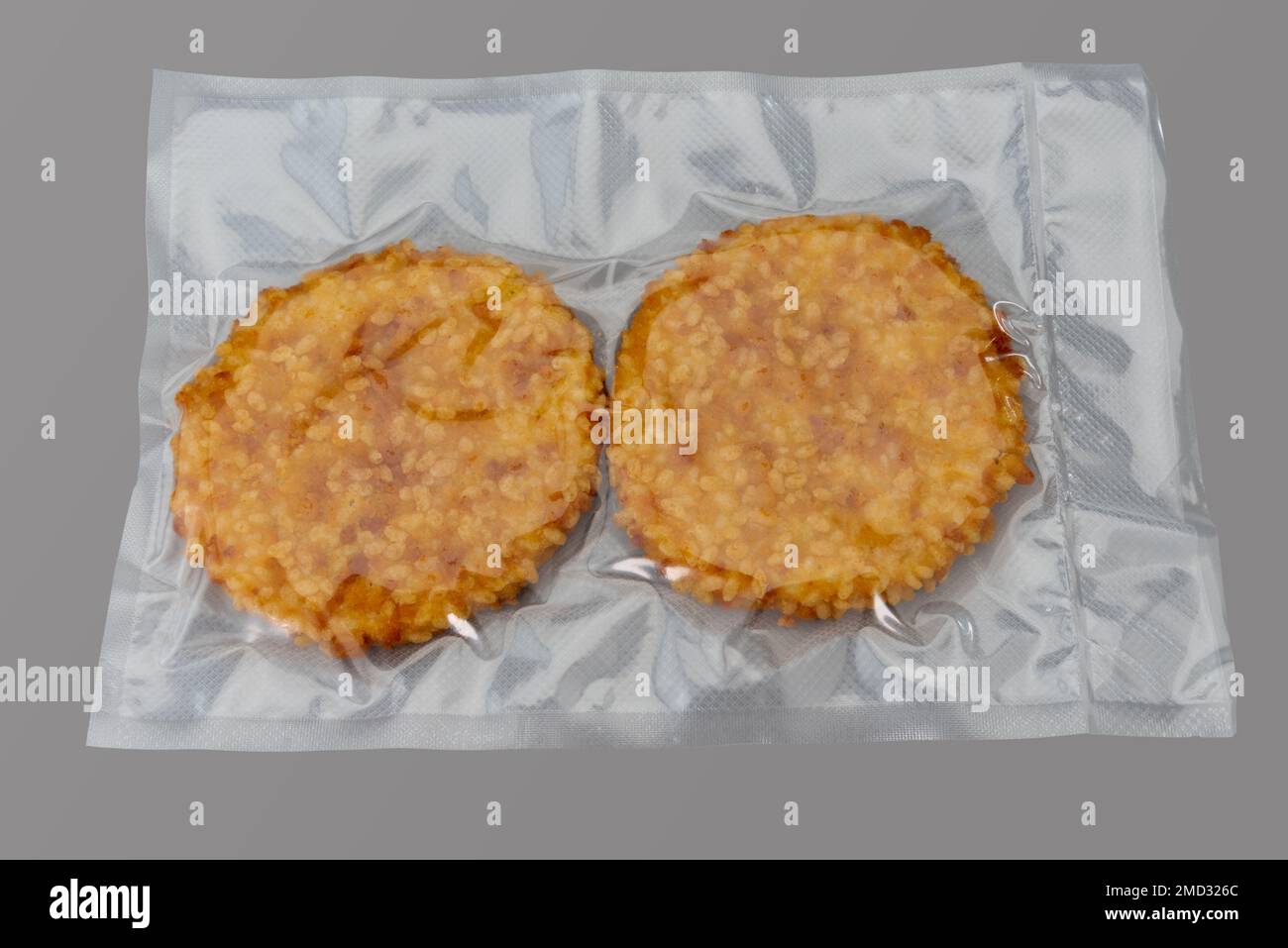 Hamburger impanato con filetto di pollo confezionato sottovuoto sigillato per una cucina sous vide isolata su sfondo grigio in vista dall'alto Foto Stock