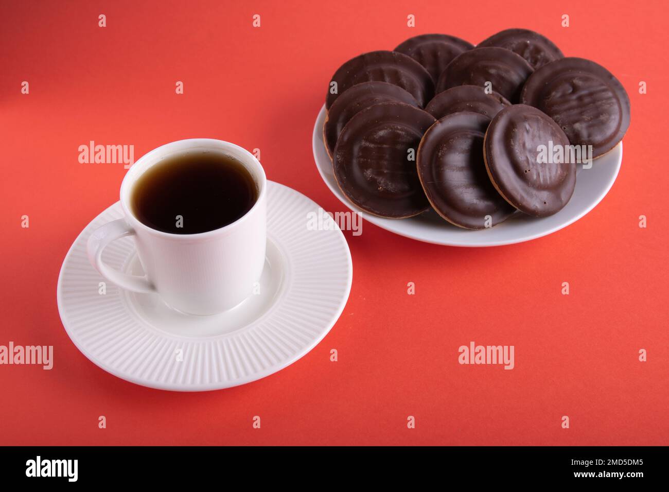 tazza fotografica di caffè e biscotti ricoperti di cioccolato in un piatto su sfondo colorato Foto Stock