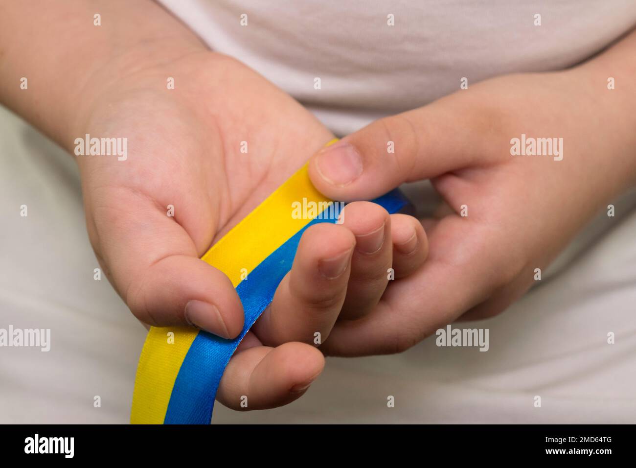 Una ragazza in una T-shirt bianca tiene un nastro giallo-blu nelle sue mani (primo piano). Bandiera dello Stato dell'Ucraina. Simbolo nazionale dell'Ucraina. Patriot Foto Stock