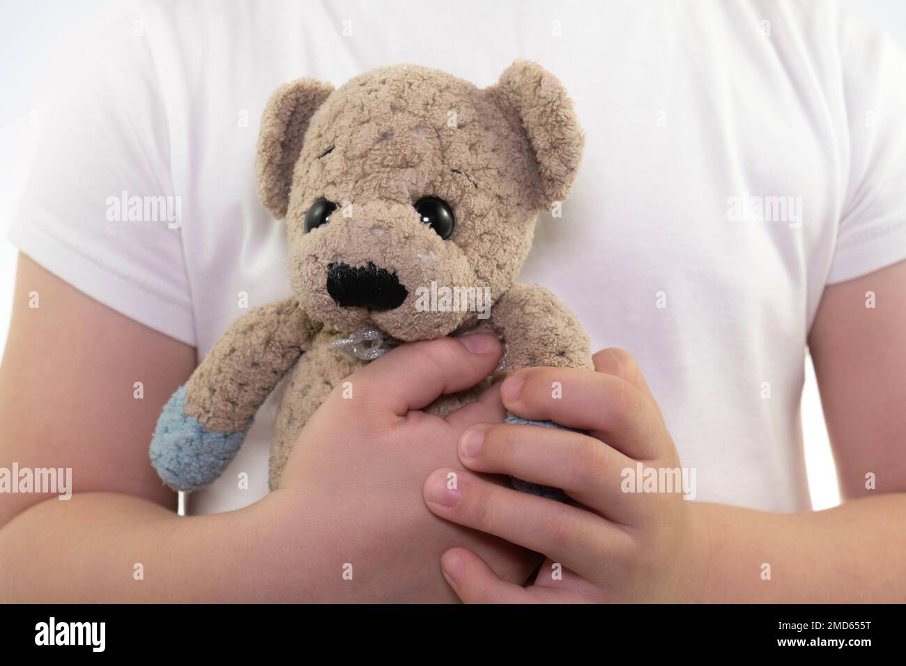 Una ragazza in una T-shirt bianca tiene un giocattolo (orsacchiotto) nelle sue mani. Gioco per bambini. Primo piano Foto Stock