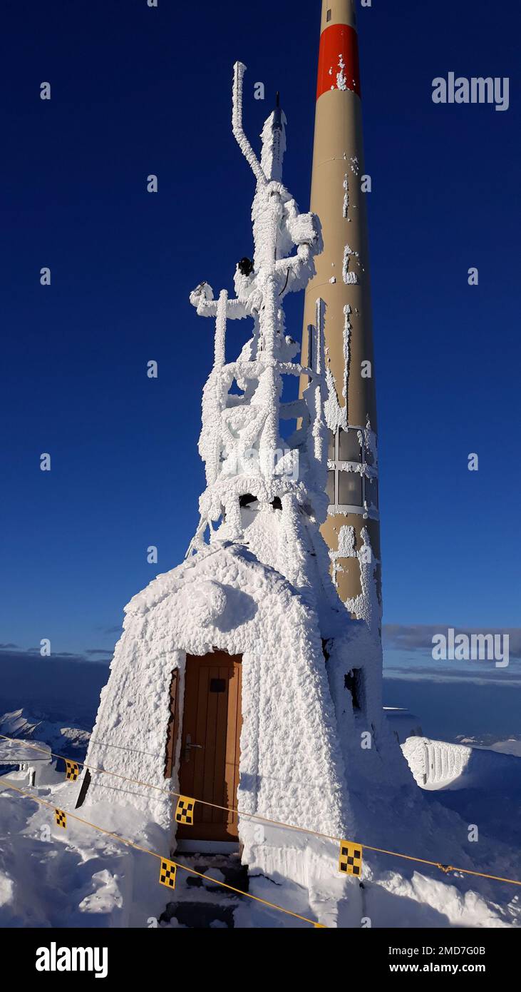 Un'antenna di trasmissione coperta di neve sulla cima di una montagna in Svizzera Foto Stock