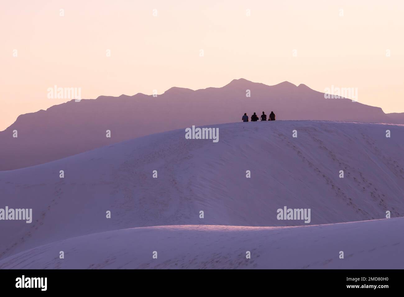 I visitatori possono ammirare il tramonto dalla cima di una duna con le San Andres Mountains lontane nel White Sands National Park, New Mexico, USA Foto Stock