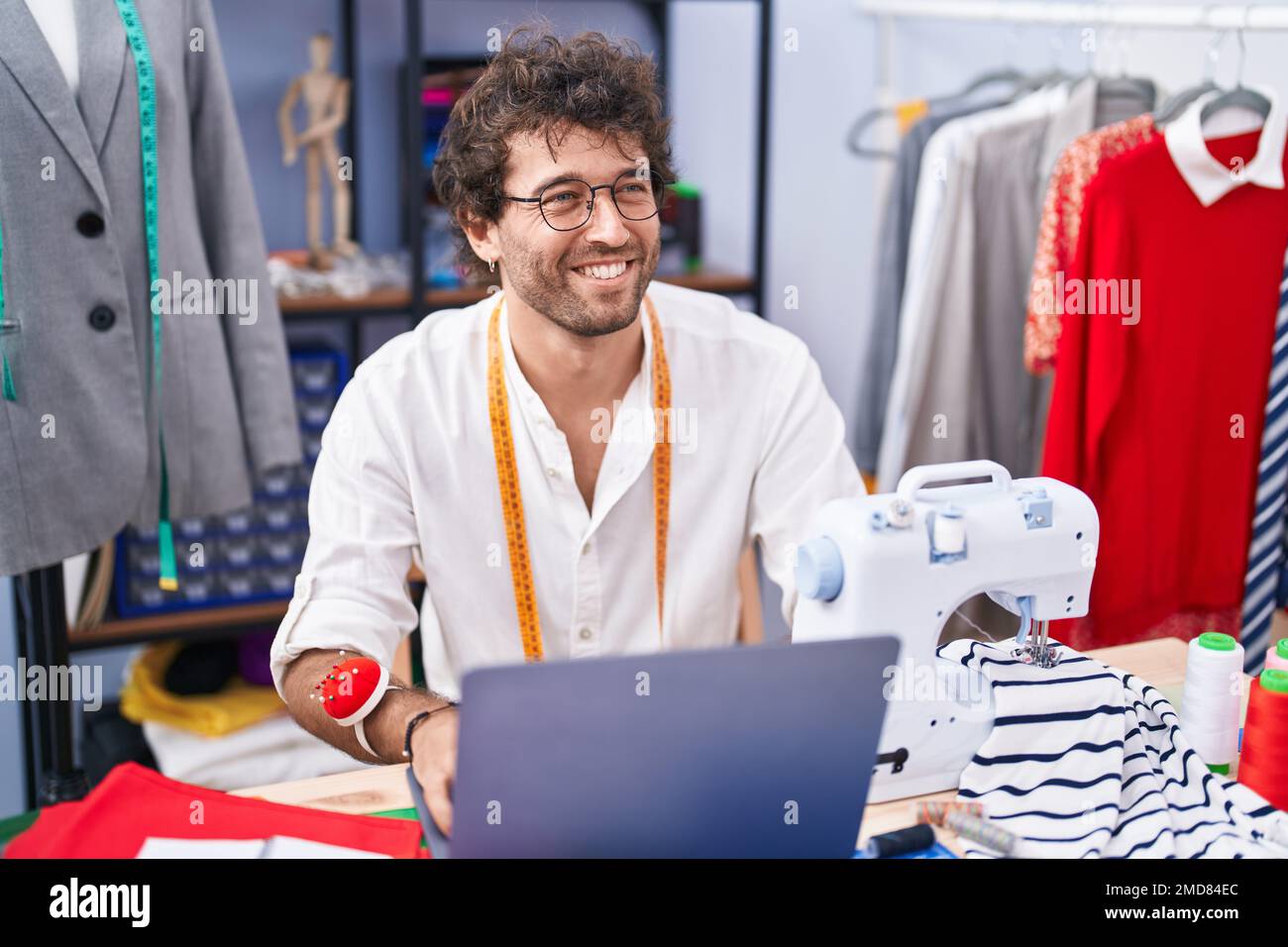 Giovane uomo ispanico su misura sorridente sicuro di usare il notebook  presso la fabbrica di abbigliamento Foto stock - Alamy