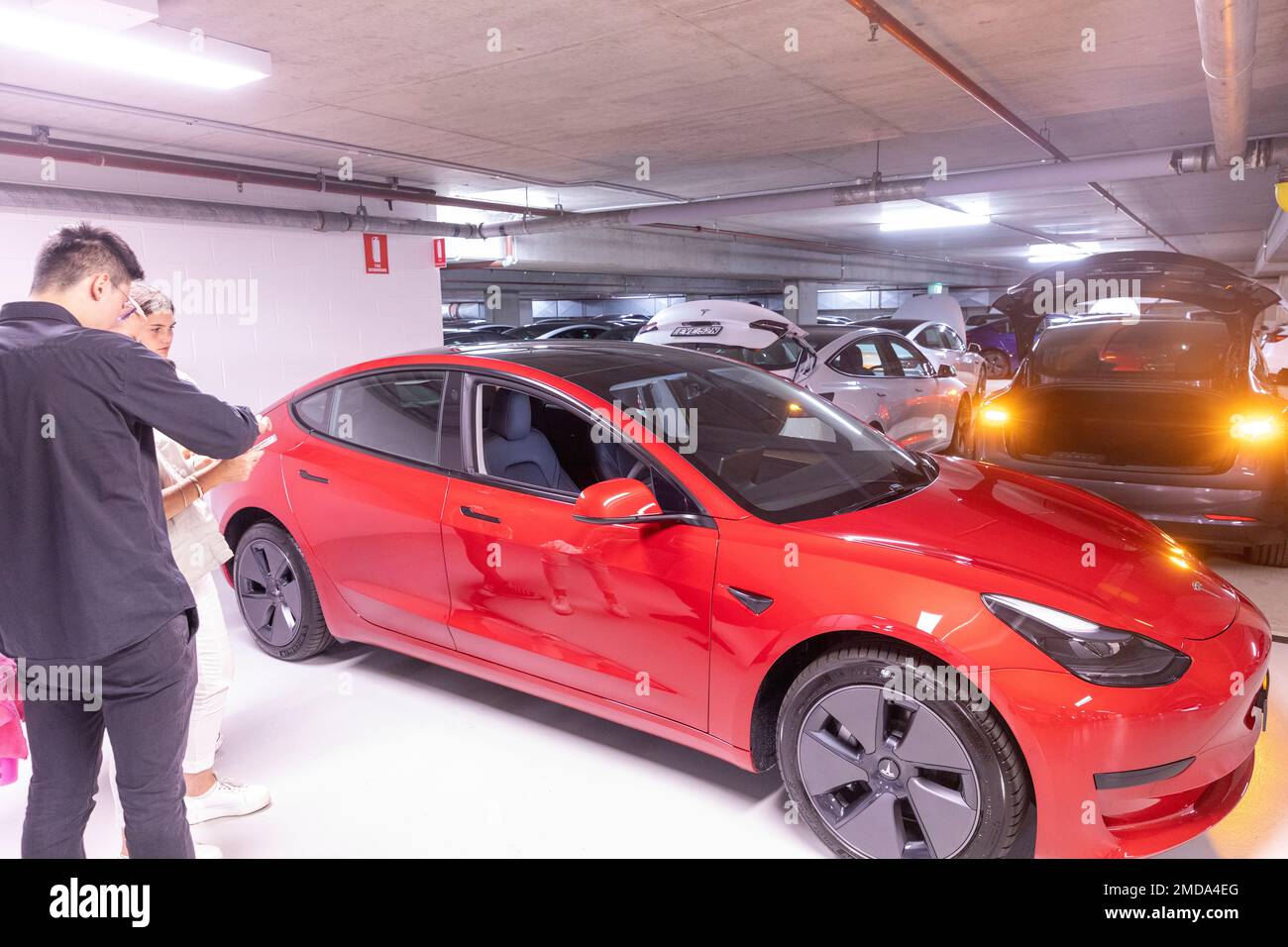 Tesla Model 3 Lady Woman ritira la sua auto nuova di zecca da Tesla e riceve istruzioni sul veicolo elettrico dal dipendente Tesla alla consegna in Australia Foto Stock