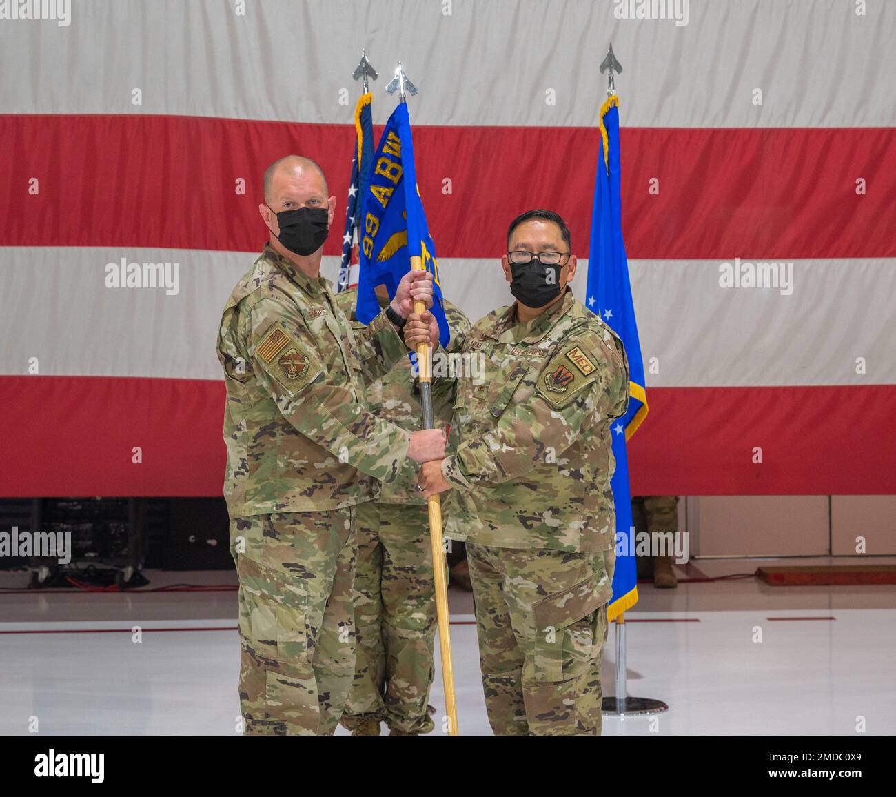 Il col. Joshua D. DeMotts, comandante della base aerea 99th, passa il guidon al comandante entrante del gruppo medico 99th, col. Ryan Mihata, 15 luglio 2022, alla base aeronautica di Nellis, Nevada. Il 99th MDG è impegnato nella preparazione operativa, nell'eccellente servizio clienti e nella fornitura di un'assistenza sanitaria di livello mondiale. Foto Stock