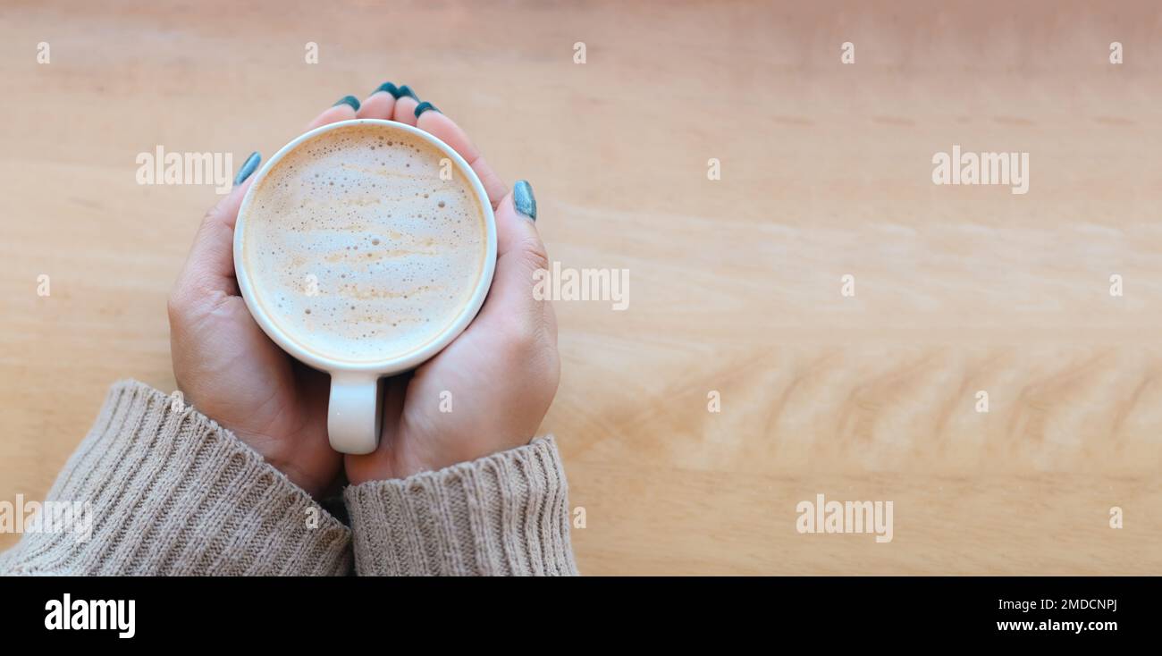 vista dall'alto caffè caramello donna caffè con mano che tiene una tazza sul tavolo di legno, caramello caffè tazza al mattino - caramello caldo macchiato Foto Stock