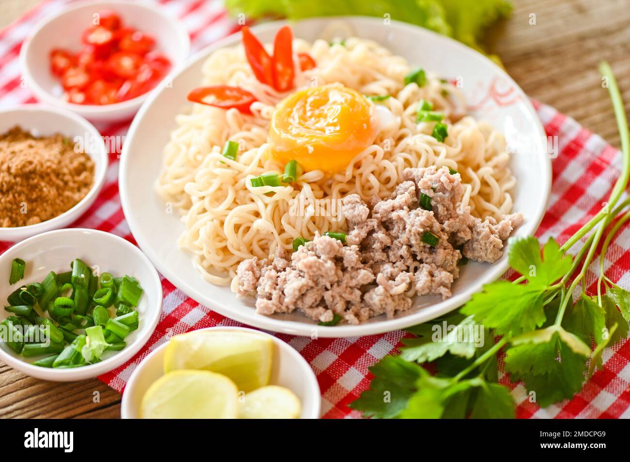 tagliatelle piatto con uova di maiale tritate verdure primavera cipolla limone lime lattuga sedano e peperoncino su cibo da tavola, spaghetti istantanei cucina gustoso mangiare spirito Foto Stock