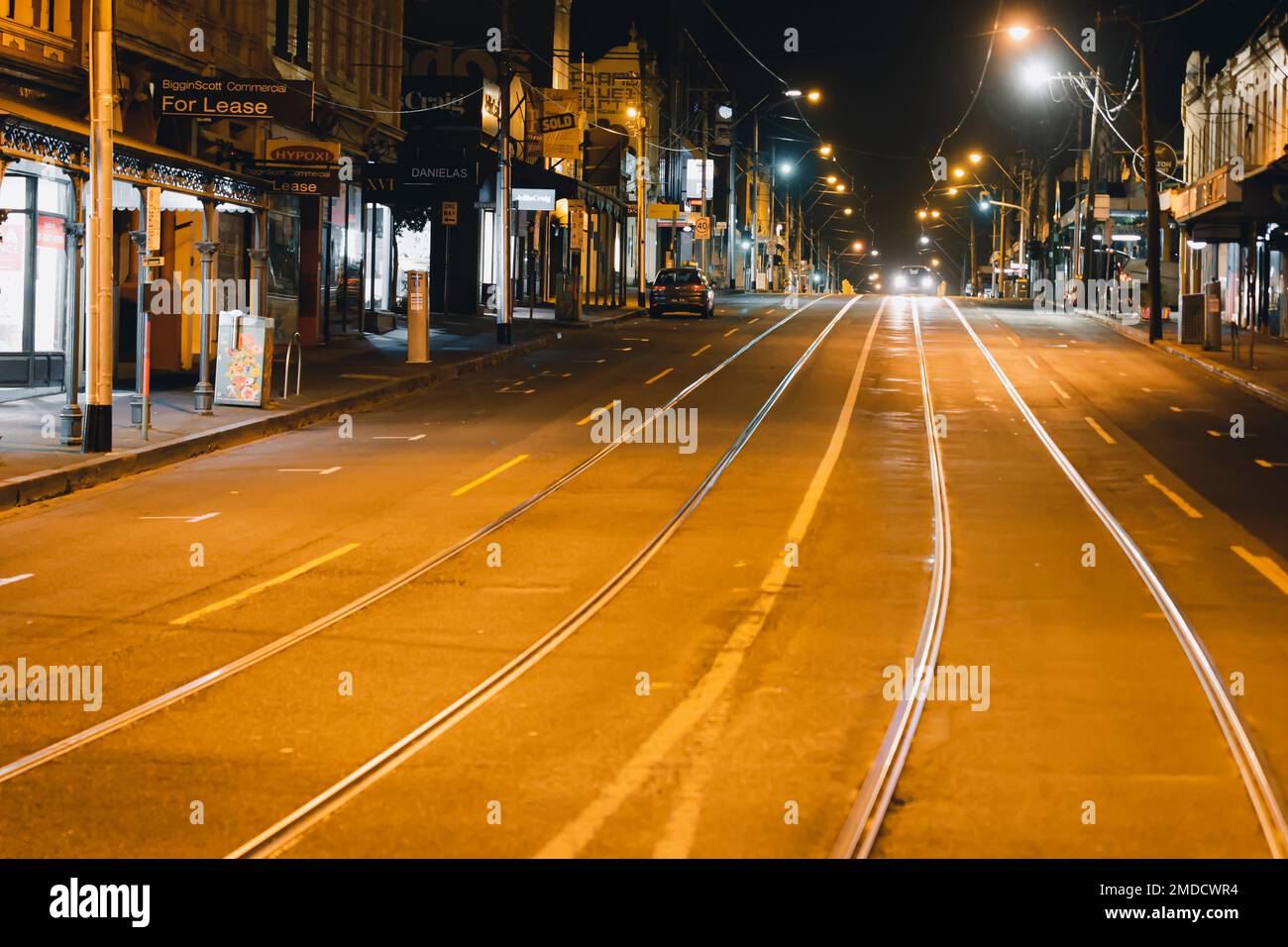 Una macchina guida attraverso la città di Melbourne di notte su una strada vuota illuminata Foto Stock