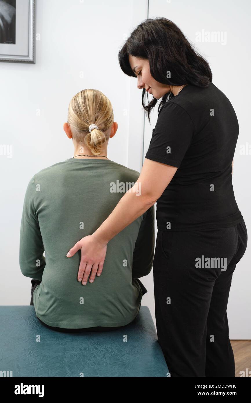 Donna osteopata terapeuta esaminare la schiena del paziente per la diagnosi e il trattamento. Assistenza sanitaria professionale e sollievo dal dolore attraverso la terapia manuale. Foto Stock