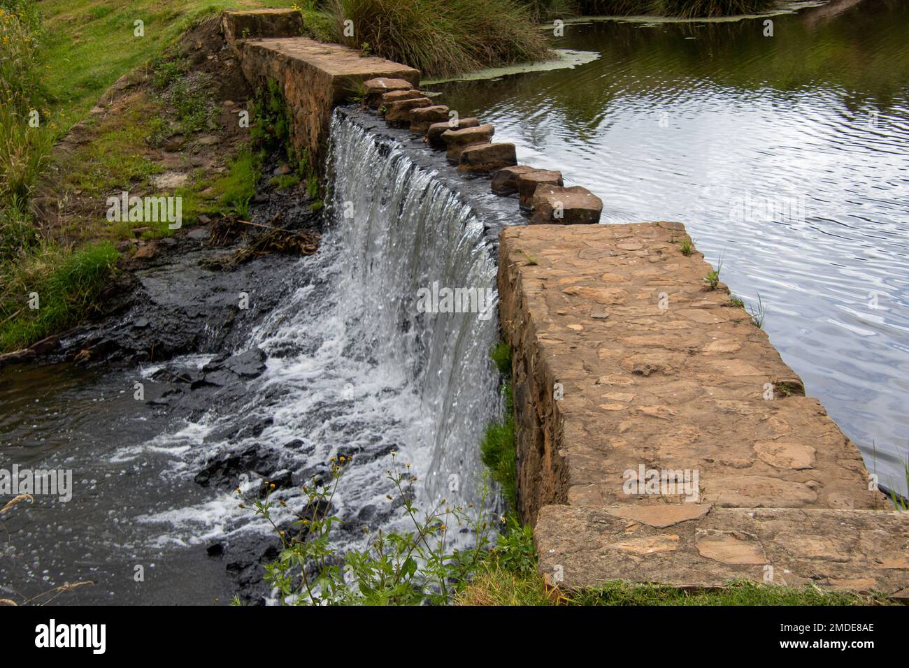 L'acqua di una sorgente scorre su uno stramazzo in campagna Foto Stock