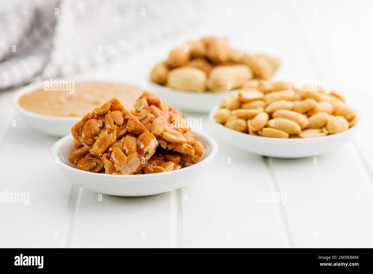 Burro di arachidi dolci, arachidi e arachidi sulla tavola bianca. Foto Stock