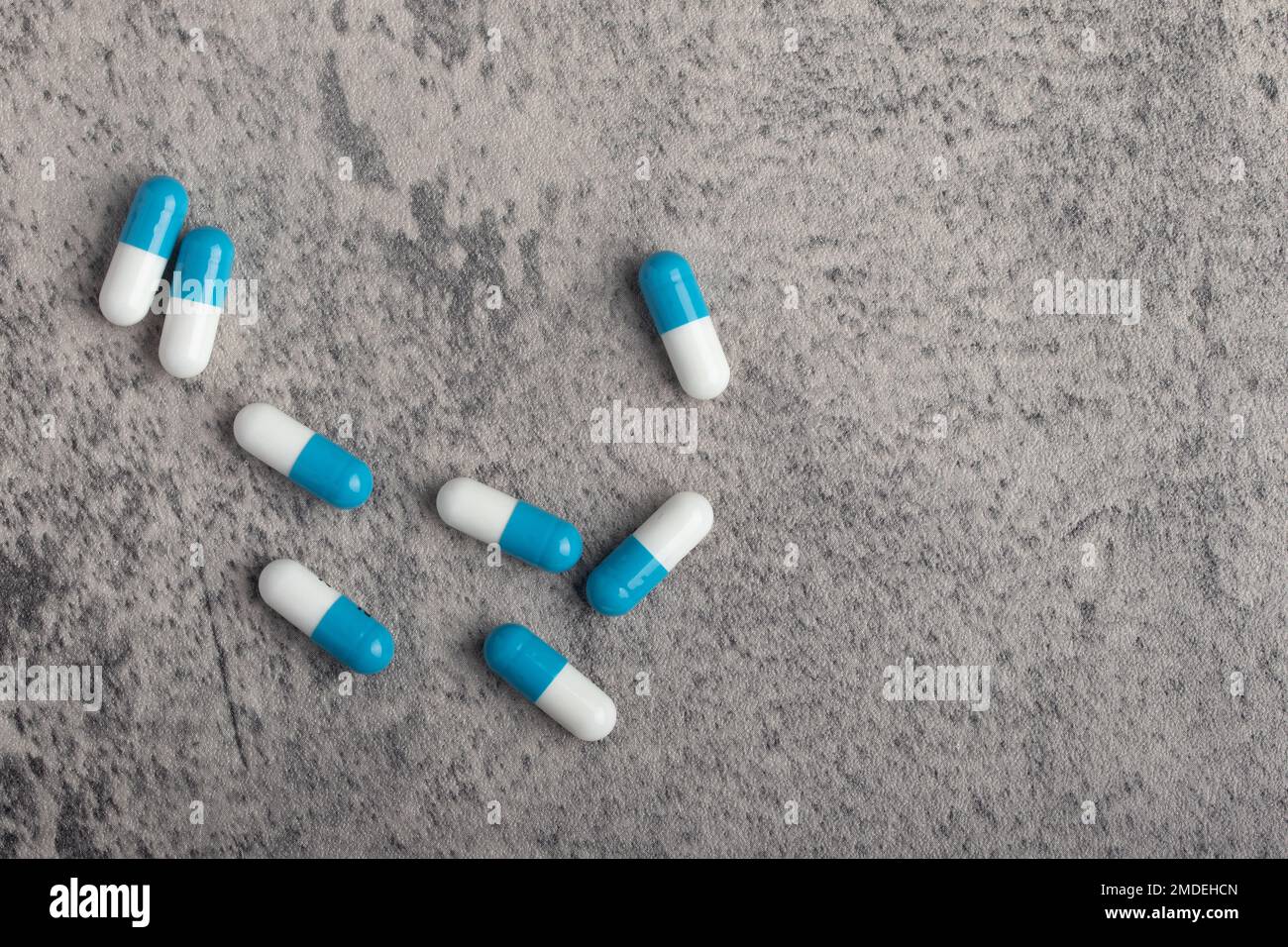 Capsula per pillola bianca e blu su sfondo grigio, messa a fuoco selettiva, spazio di copia. Foto Stock