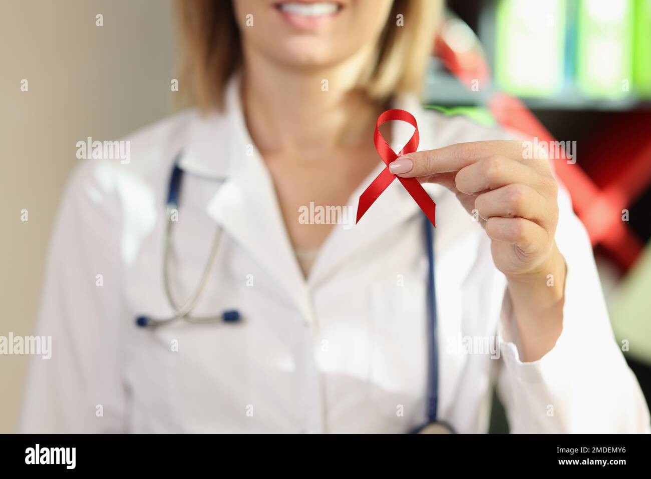 Medico femminile che tiene il nastro rosso - simbolo della malattia di AIDS. Foto Stock