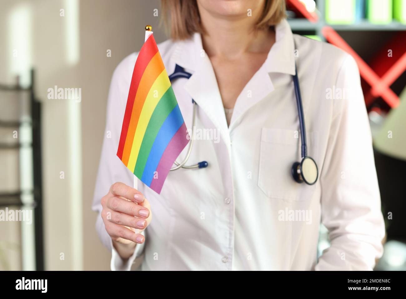 Donna medico mostra lgbt bandiera di orgoglio in mano in ospedale ufficio. Foto Stock