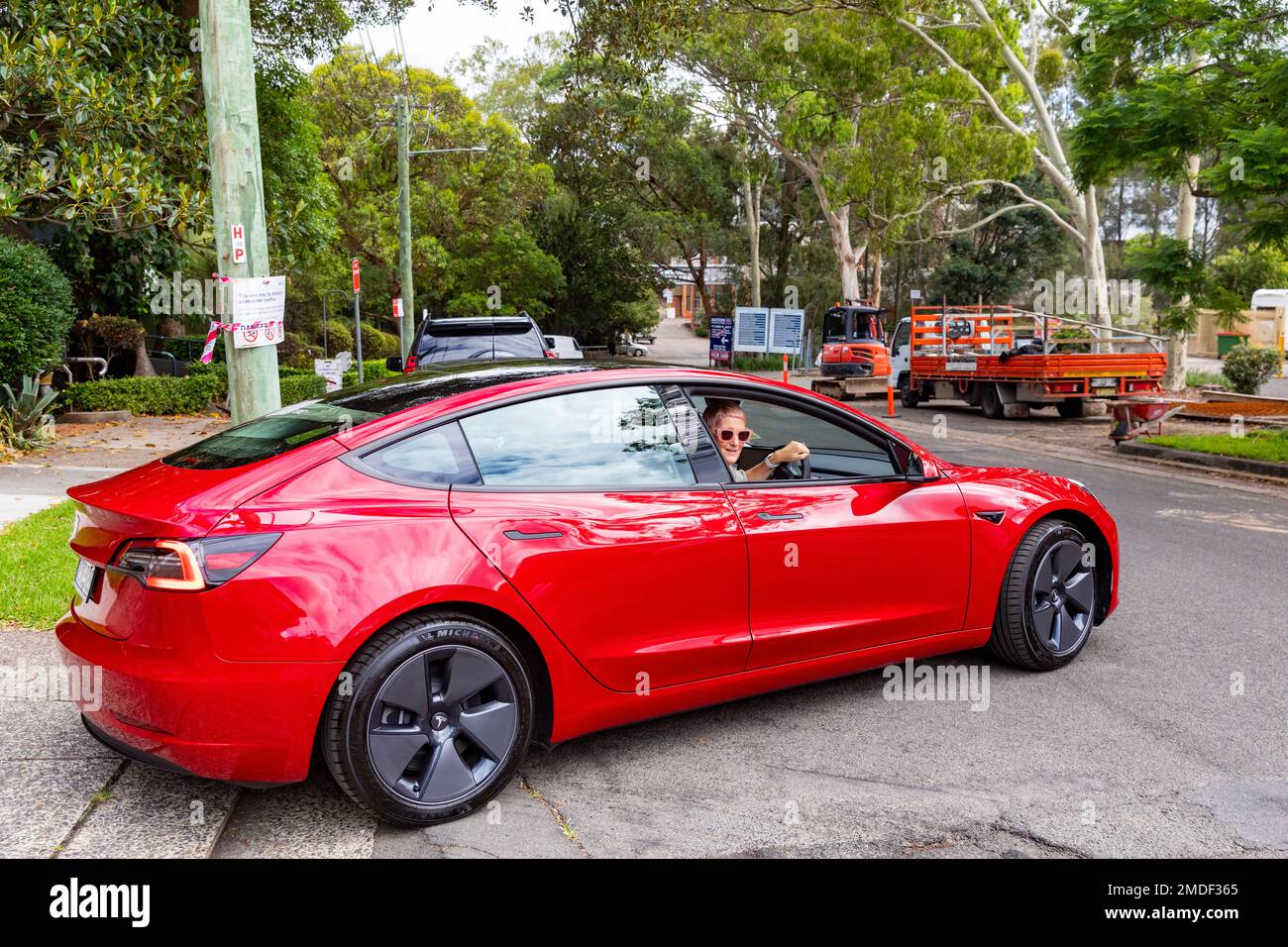 Red Tesla Model 3, modello rilasciato donna e auto, donna guida la sua nuova auto dalla concessionaria Tesla a Sydney, NSW, Australia Foto Stock