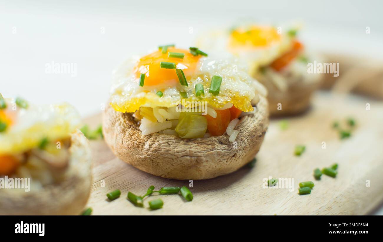 Funghi farciti con riso e un uovo di quaglia fritto. Tradizionale tapa spagnola. Foto Stock