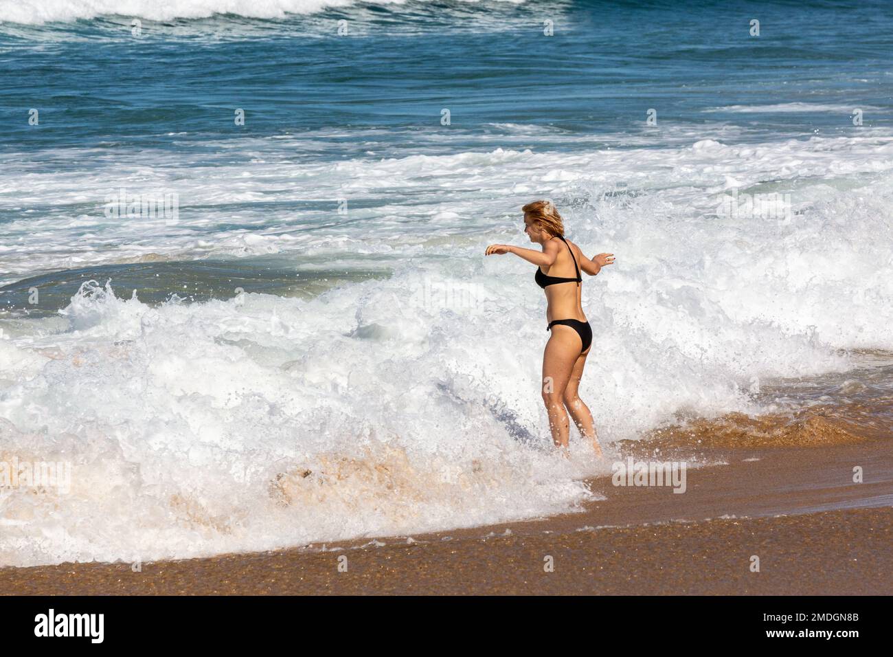 Giovane donna che ha un buon tempo lasciandosi accarezzare dalle onde. Cofete Beach, Fuerteventura, Isole Canarie Foto Stock