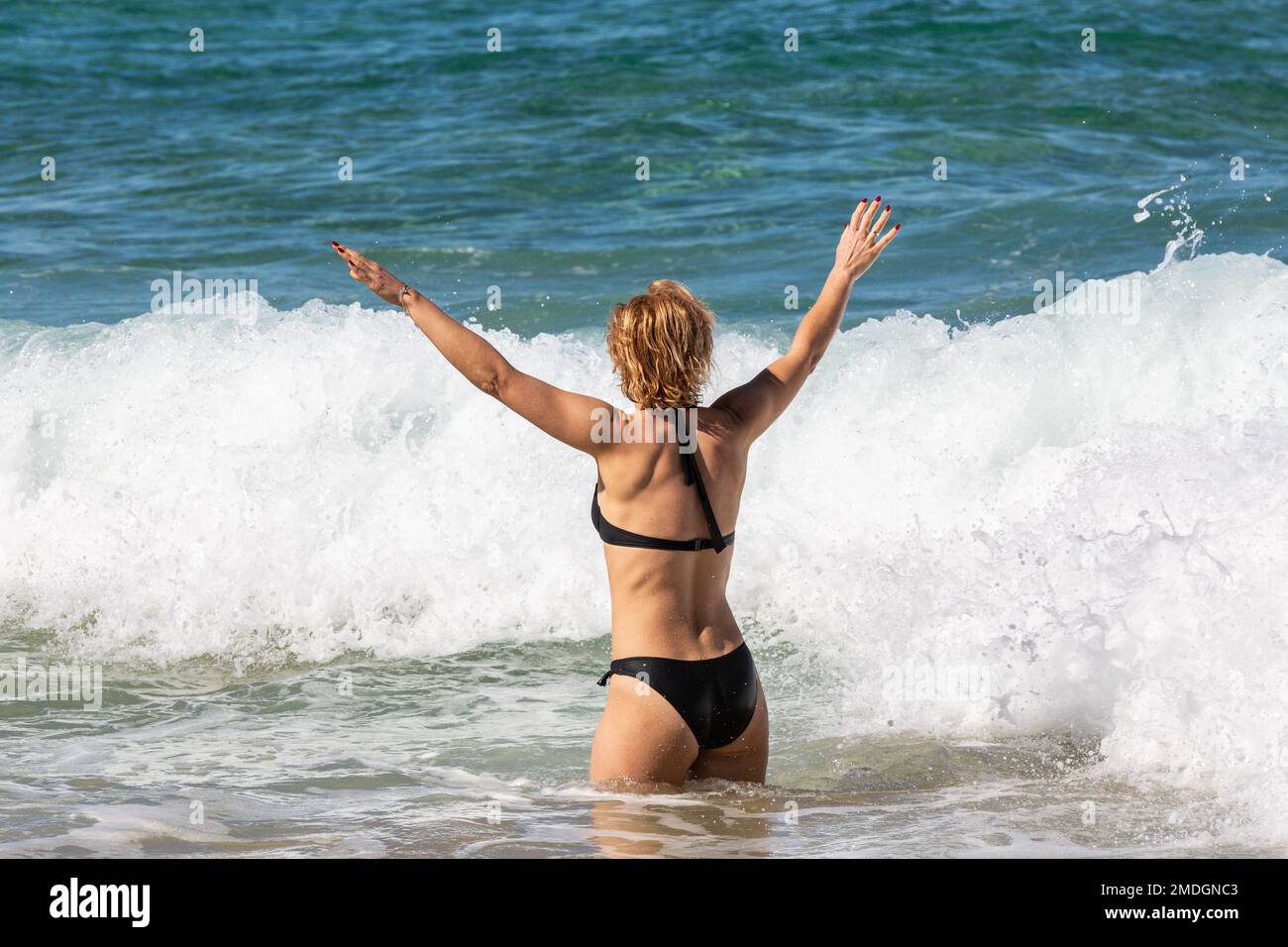 Giovane donna che ha un buon tempo lasciandosi accarezzare dalle onde. Cofete Beach, Fuerteventura, Isole Canarie Foto Stock