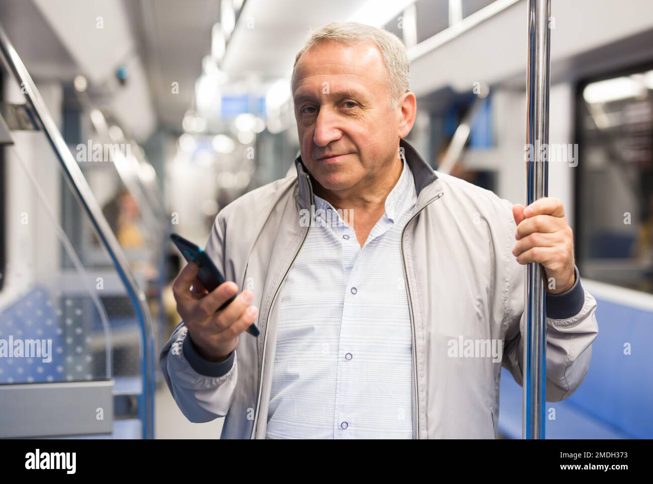 Uomo di mezza età con smartphone in metropolitana Foto Stock
