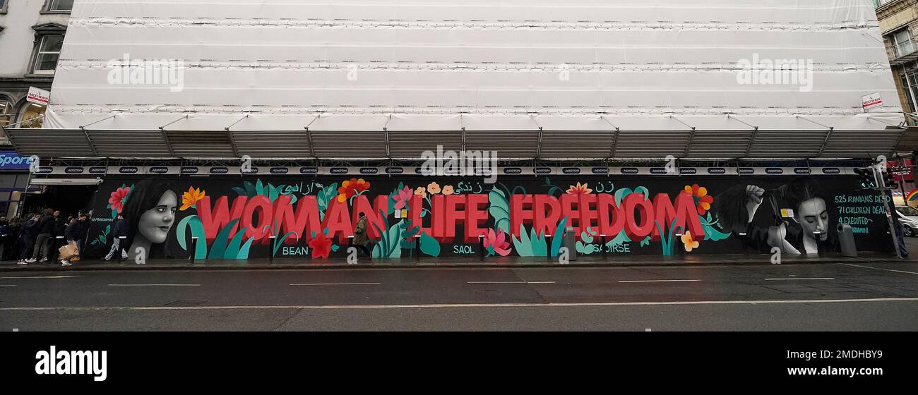 La gente passa davanti a un murale che mette in luce la situazione delle donne in Iran, in Dame Street a Dublino. Il Mural, di un gruppo di artisti femminili noti come il collettivo Minaw, ha le parole "Woman Life Freedom" in inglese, irlandese e persiano, e presenta un'immagine di Masha Amini di 22 anni. A metà settembre sono scoppiate proteste in Iran in seguito alla morte della signora Amini, che è morta dopo essere stata arrestata dalla polizia morale iraniana per aver presunto violato il rigoroso codice di abbigliamento della Repubblica islamica. Centinaia di persone sono state uccise e migliaia sono state arrestate durante manifestazioni sulle circostanze della sua morte. Immagine Foto Stock