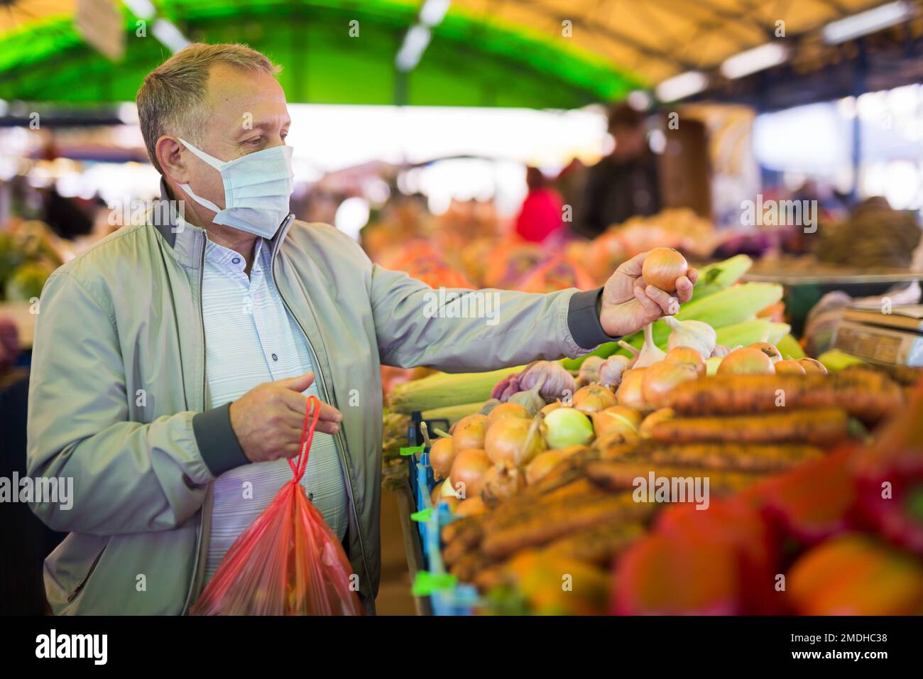 Uomo di mezza età in maschera di acquisto cipolle Foto Stock
