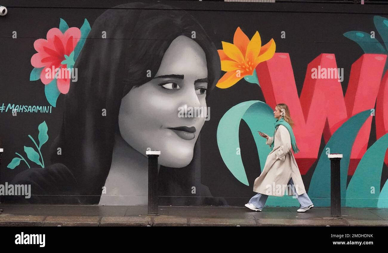 La gente passa davanti a un murale che mette in luce la situazione delle donne in Iran, in Dame Street a Dublino. Il Mural, di un gruppo di artisti femminili noti come il collettivo Minaw, ha le parole "Woman Life Freedom" in inglese, irlandese e persiano, e presenta un'immagine di Masha Amini di 22 anni. A metà settembre sono scoppiate proteste in Iran in seguito alla morte della signora Amini, che è morta dopo essere stata arrestata dalla polizia morale iraniana per aver presunto violato il rigoroso codice di abbigliamento della Repubblica islamica. Centinaia di persone sono state uccise e migliaia sono state arrestate durante manifestazioni sulle circostanze della sua morte. Immagine Foto Stock