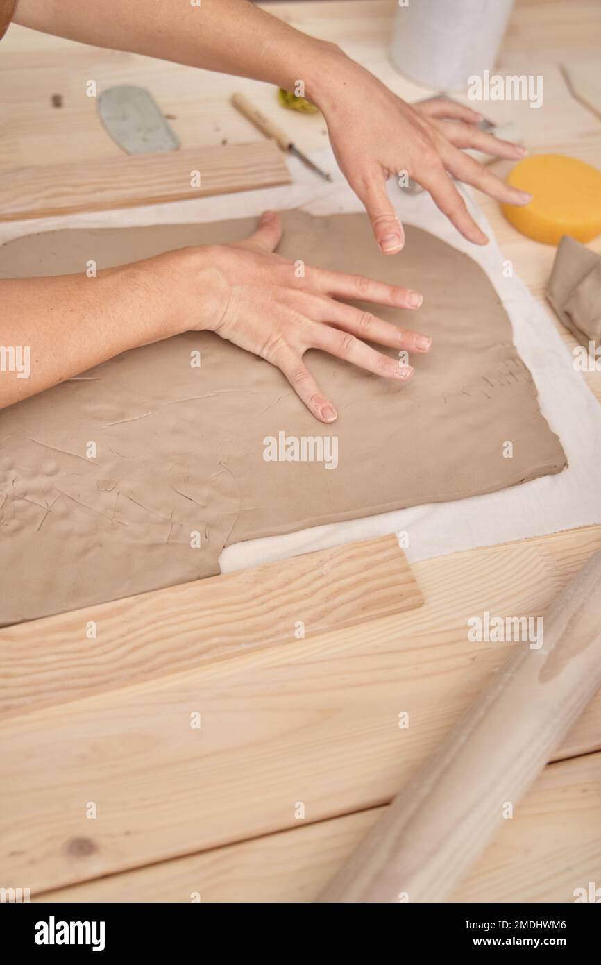 Donna che misura l'argilla con le mani in un laboratorio di ceramica. Donna che impara a lavorare la classe Crafts argilla. Foto Stock