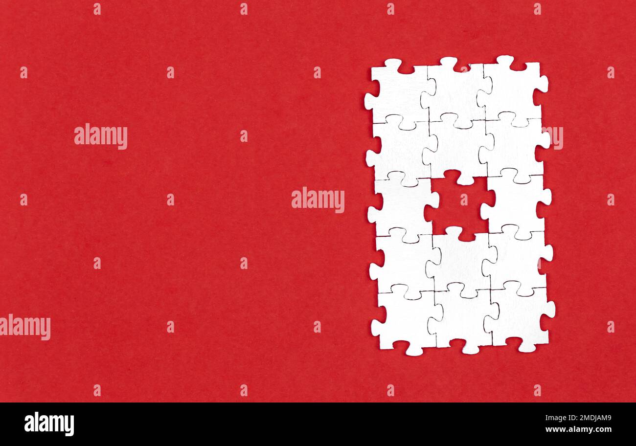 Puzzle bianchi su sfondo rosso, piatto. Foto Stock