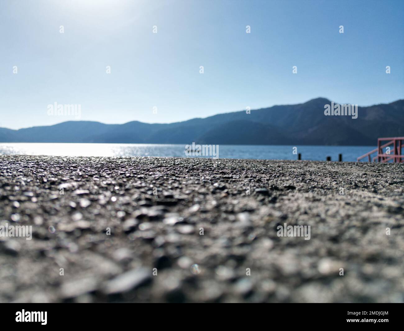 L'asfalto grigio scuro sullo sfondo del lago blu e delle montagne. Foto Stock