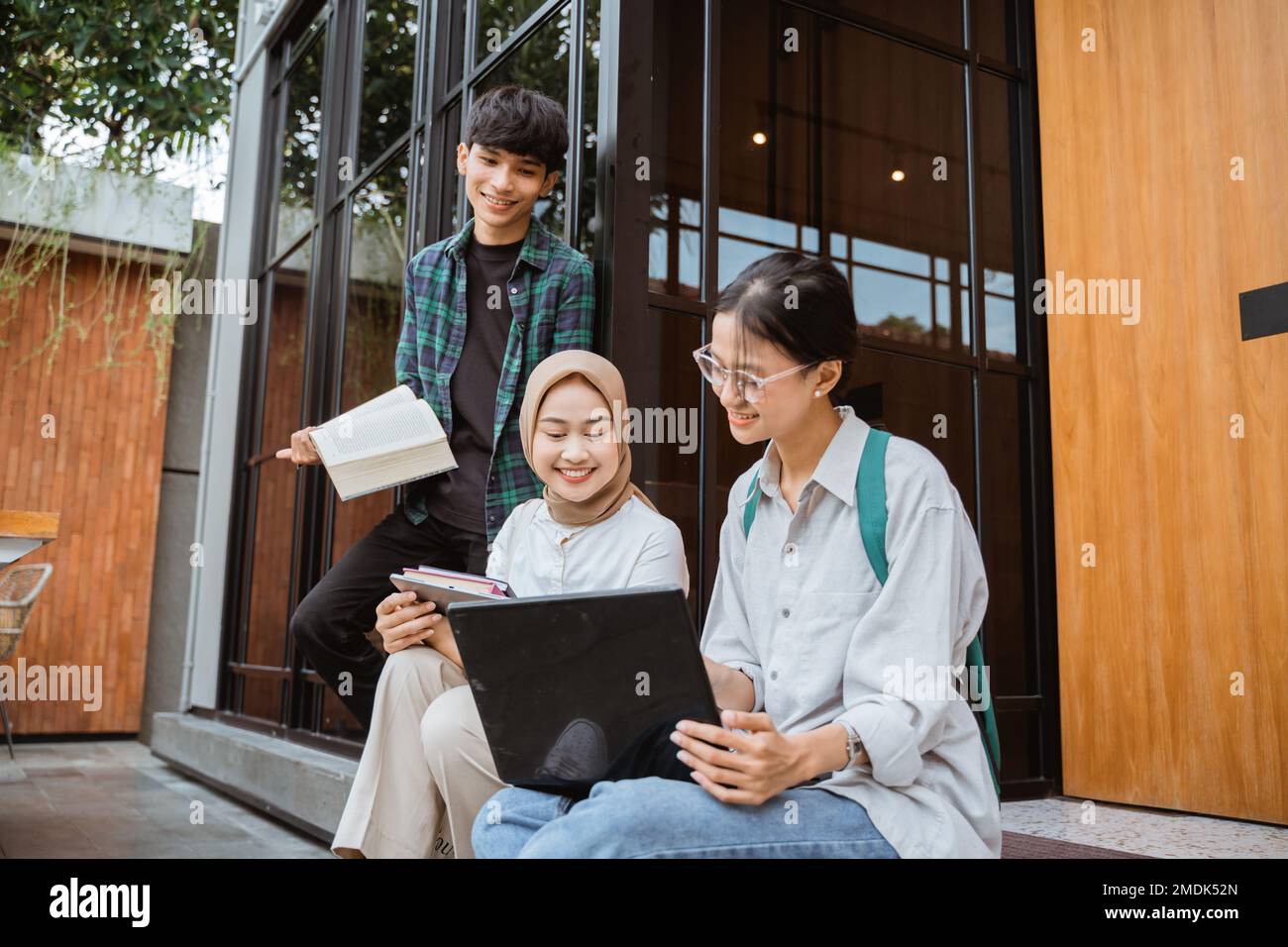 Giovani studenti universitari che utilizzano un computer portatile per  lavorare vicino a finestre di vetro Foto stock - Alamy