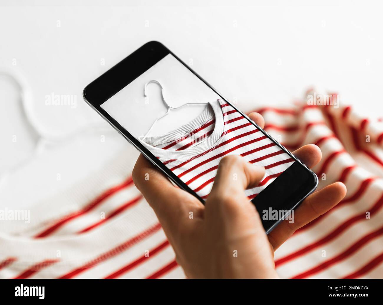 Uomo che scatta una foto della t-shirt a righe sullo smartphone. Foto Stock