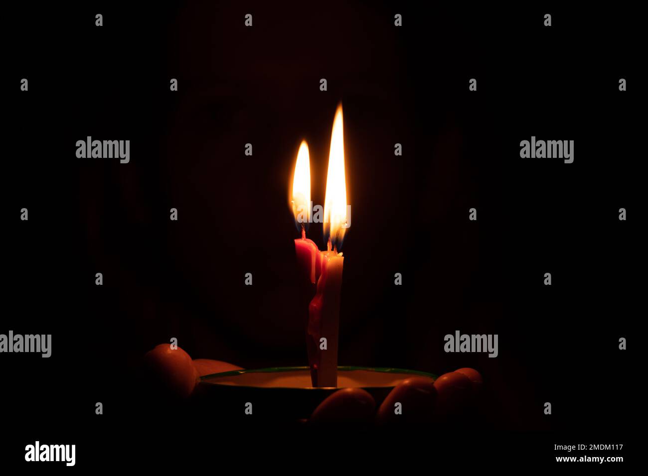mano femmina che tiene una candela bruciante al buio, fiamma di candela di notte Foto Stock