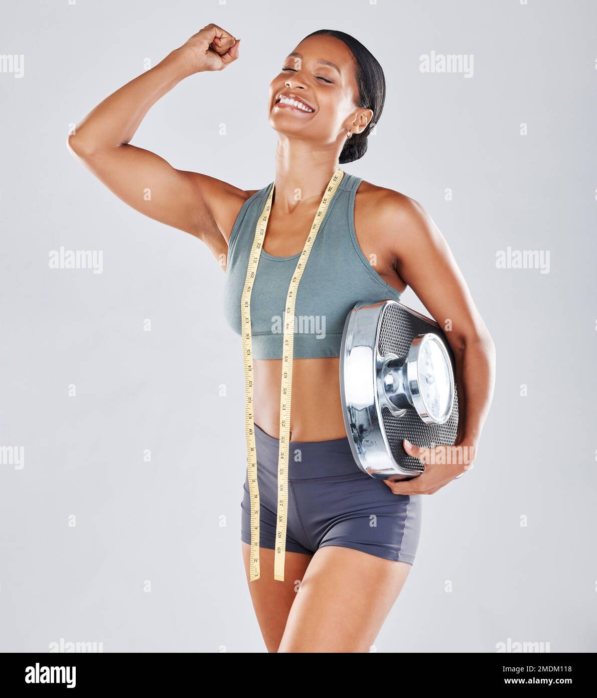 Donna nera, scala e corpo sottile in felice successo, vittoria o vincere per una dieta sana contro uno sfondo grigio studio. Modello femminile afro-americano Foto Stock