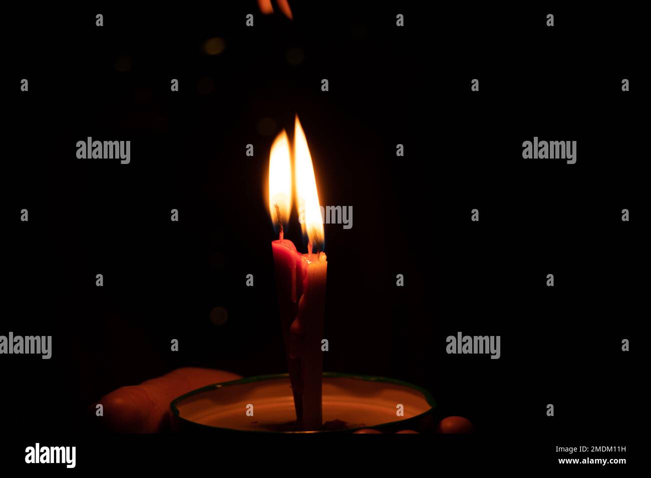mano femmina che tiene una candela bruciante al buio, fiamma di candela di notte Foto Stock