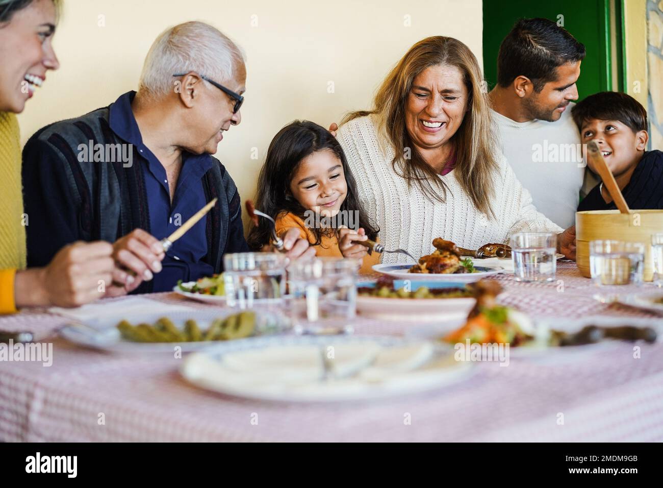 Felice famiglia latina divertirsi mangiando insieme a casa - Focus sulla faccia della nonna Foto Stock