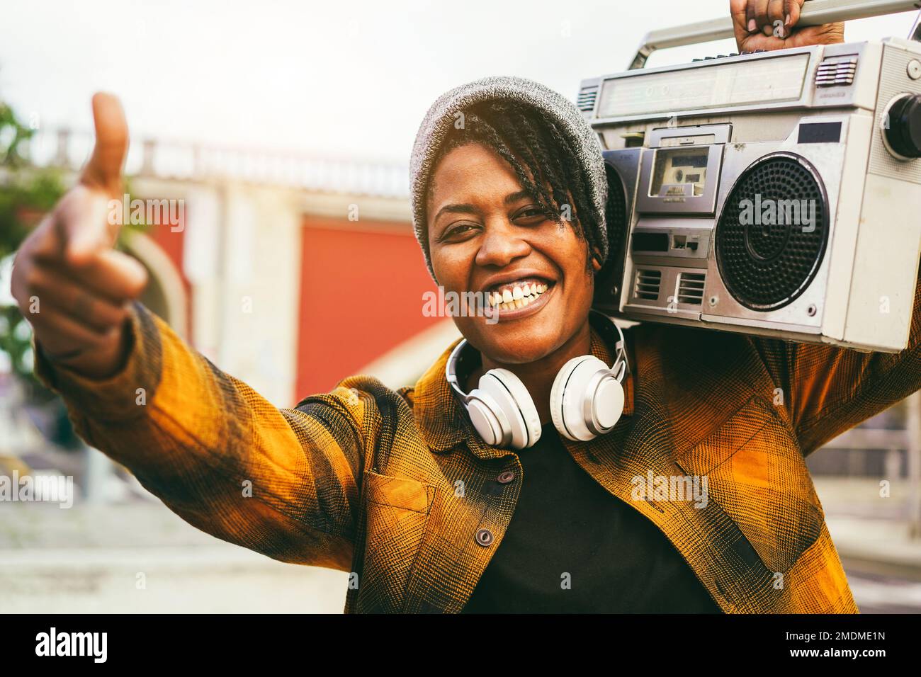 Donna afroamericana che ascolta musica da stereo boombox vintage con strade cittadine in background - stile di vita sotterraneo e concetto rap - Focus on Foto Stock