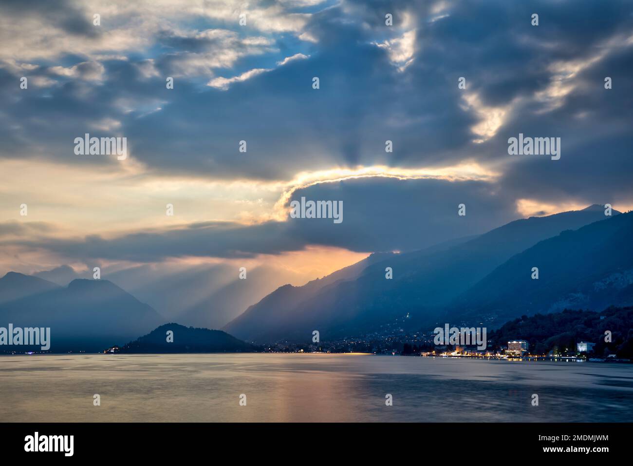 in tarda serata d'estate al lago di como con montagne nocciole e raggi di sole che brillano attraverso le nuvole Foto Stock