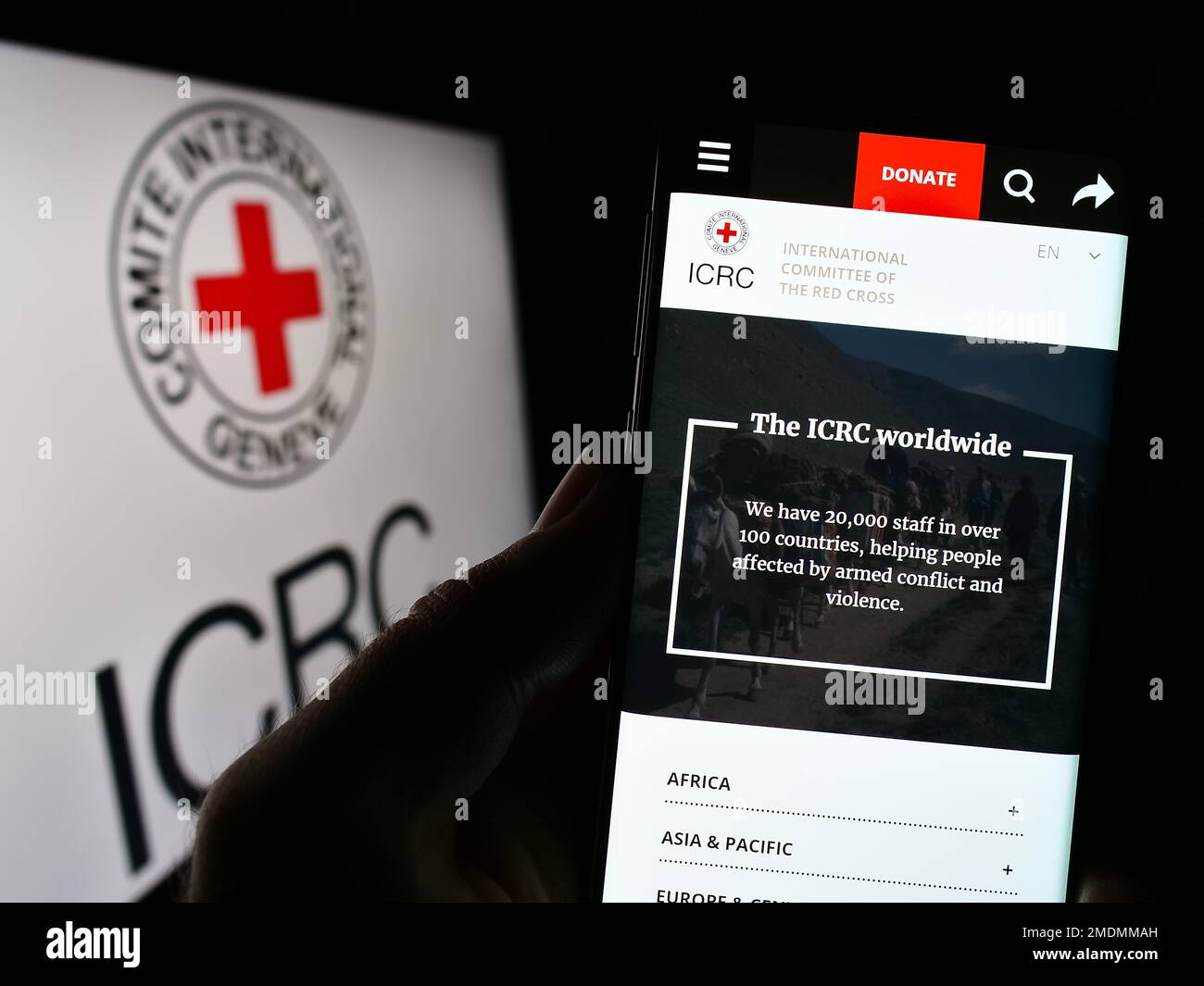 Persona che tiene uno smartphone con una pagina web del Comitato Internazionale della Croce Rossa (CICR) sullo schermo con il logo. Messa a fuoco al centro del display del telefono. Foto Stock