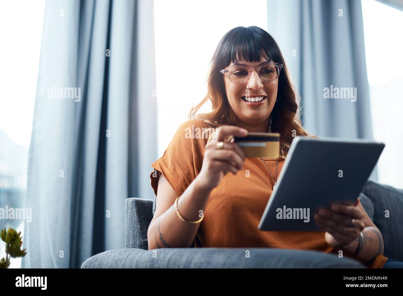 È il momento di effettuare il check-out. una giovane donna che tiene la sua carta di credito mentre usa un tablet digitale. Foto Stock