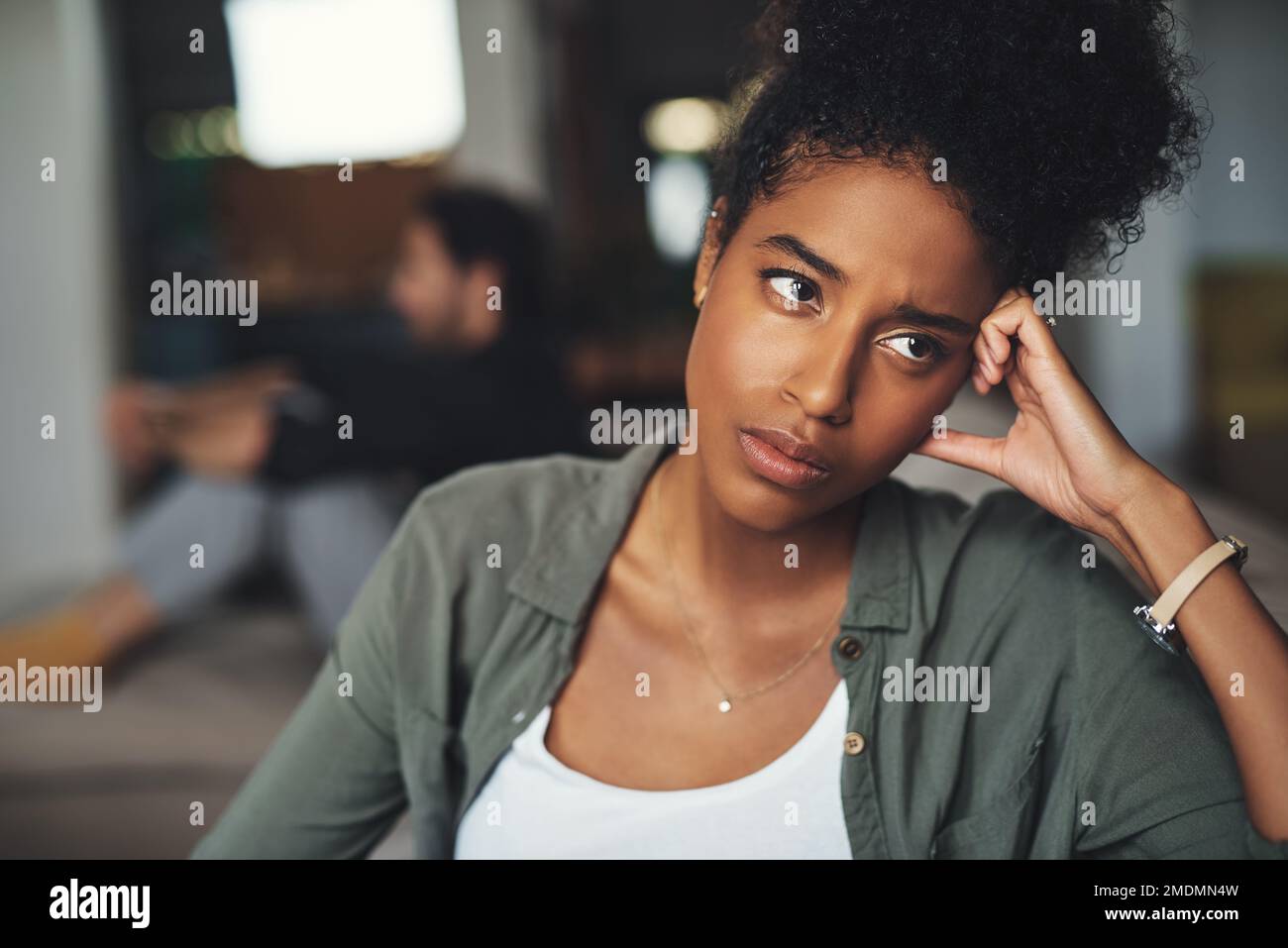 Nulla sarà più lo stesso. una giovane donna attraente che guarda turbata mentre il suo ragazzo si siede sullo sfondo a casa. Foto Stock