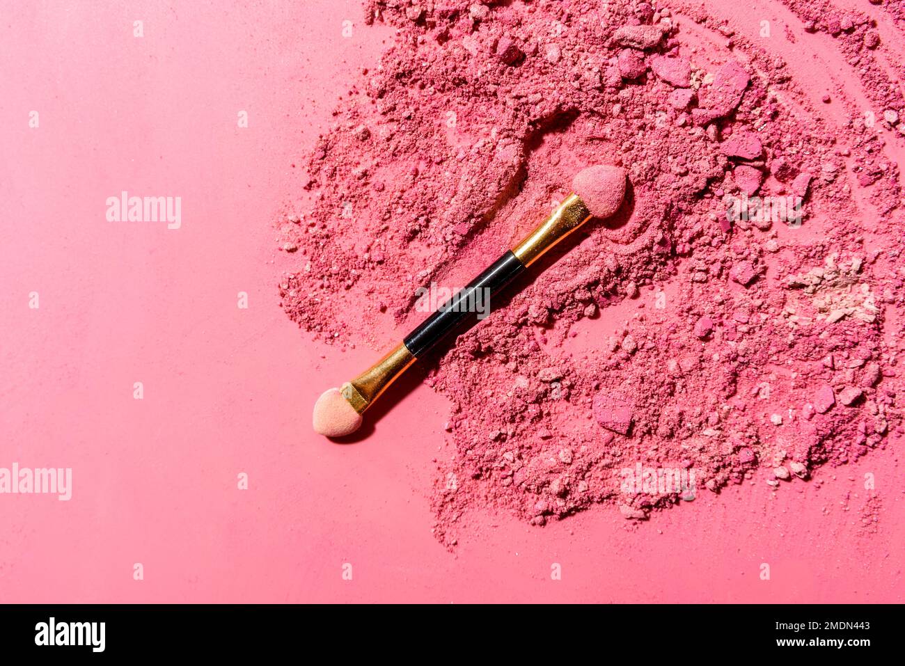 Ombre oculari rosa schiacciate con pennello o strumento di miscelazione applicatore su sfondo rosa Foto Stock