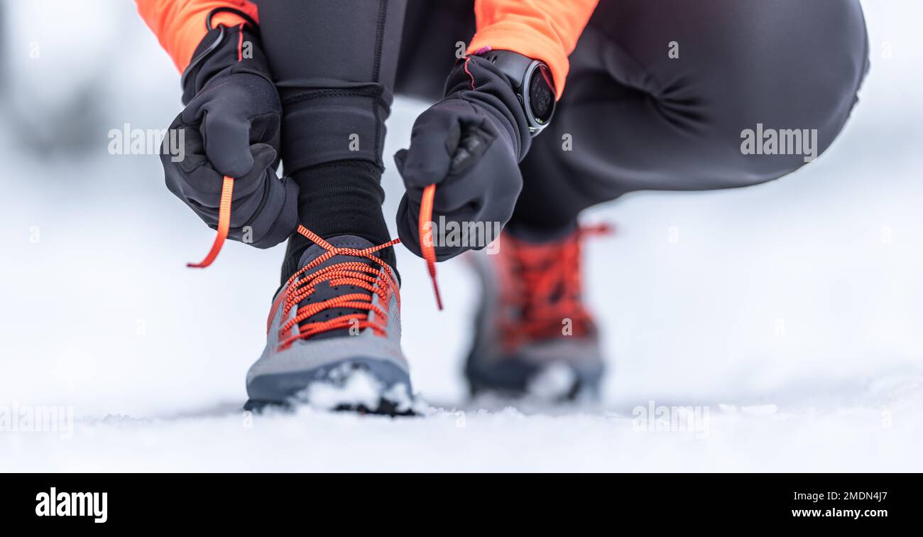 Una vista ravvicinata di una runner che legava le scarpe prima di allenarsi sulla neve nella stagione invernale. Foto Stock