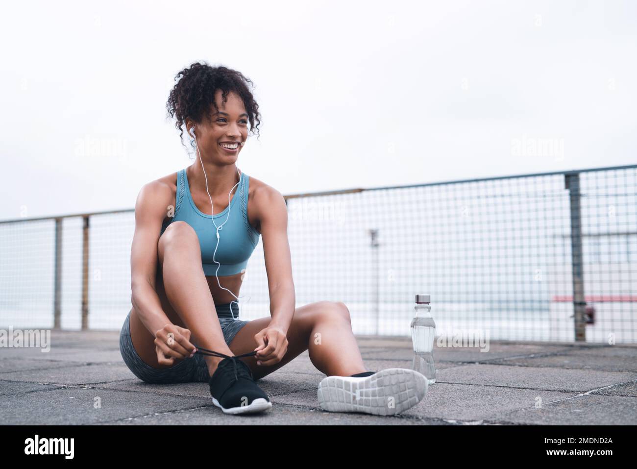 Im tutto sicuro per il viaggio in avanti. una giovane donna sportiva che le lega i merletti mentre si esercita all'aperto. Foto Stock