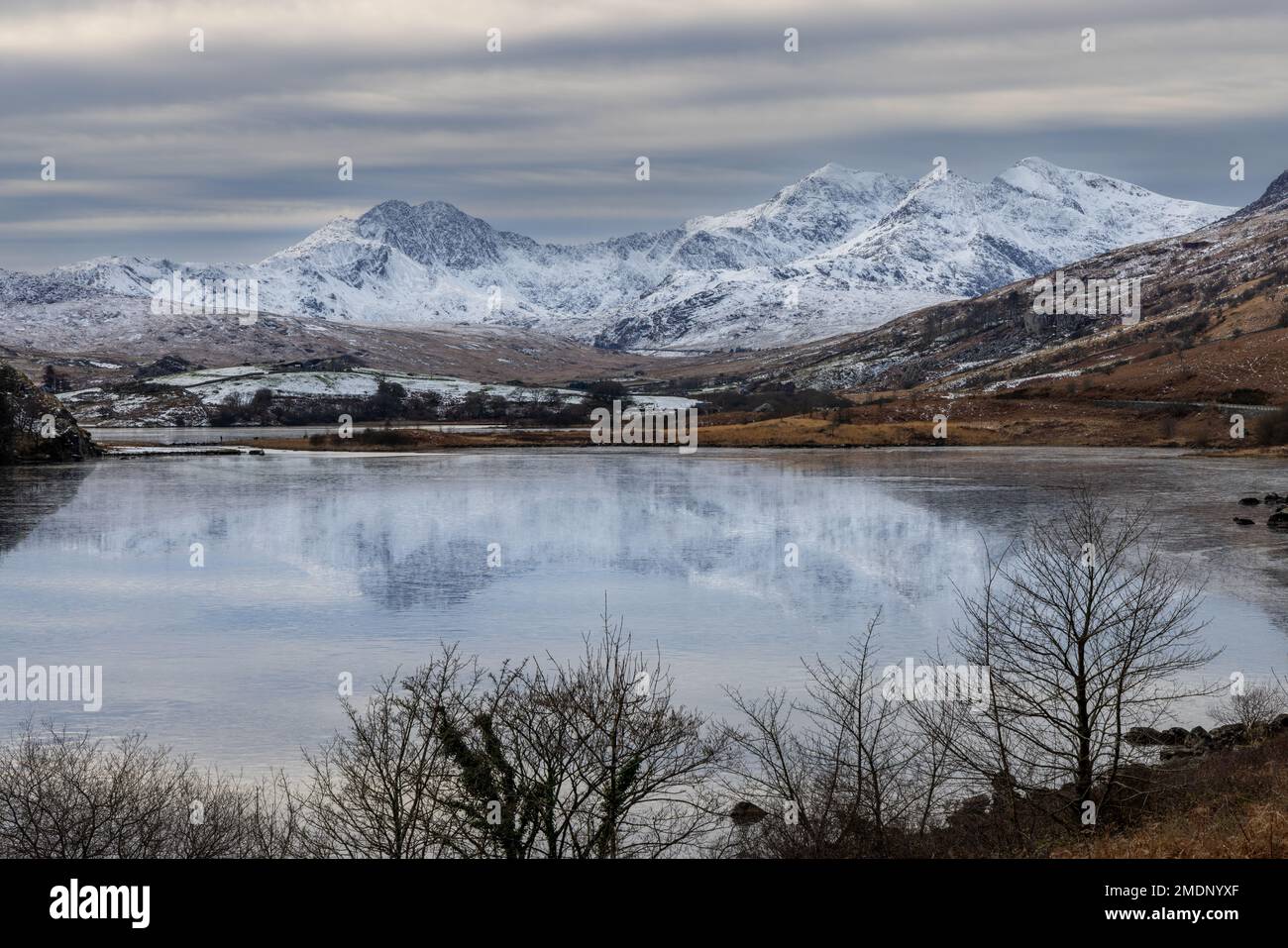 In una giornata gelida e innevata, Lliwedd, Yr Wyddfa (Snowdon) e Crib Goch visti in primo piano attraverso Llyn Mymbyr Foto Stock
