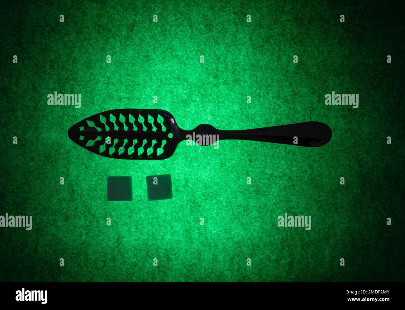 Classico cucchiaio d'assenzio a taglio e cubetti di zucchero su fondo verde Foto Stock