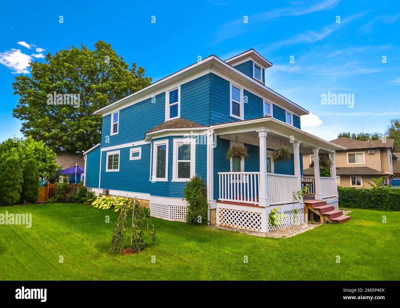 Storica casa di famiglia con prato verde di fronte e cielo blu sfondo. Foto Stock