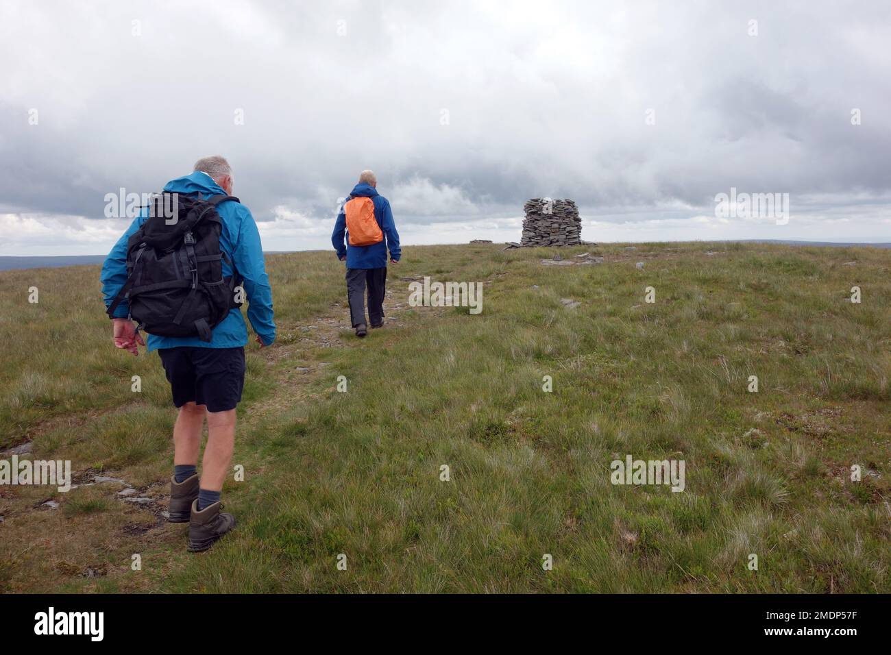 Due anziani a piedi il Cairn pietra sulla cima di 'Lovely Seat' a Wensleydale nel Yorkshire Dales National Park, Inghilterra, Regno Unito. Foto Stock