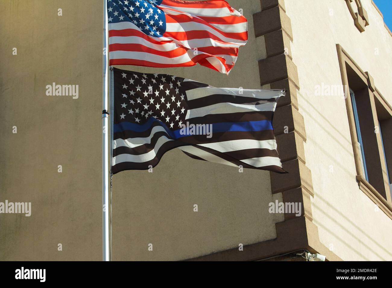 Bandiera blu sottile dell'applicazione della legge che vola su un palo sotto la bandiera degli Stati Uniti in un quartiere di New York City Foto Stock